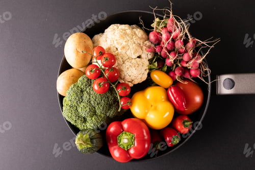 Preview: Overhead close-up of various colorful vegetables in frying pan on black background
