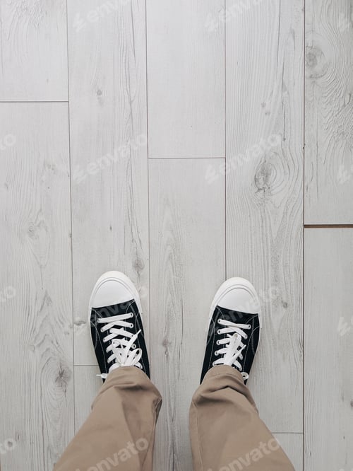 Preview: Male legs in black sneakers stand on a gray wooden floor