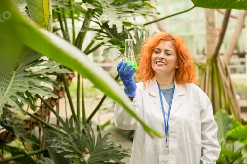 Preview: Scientist examining a glass container with green liquid