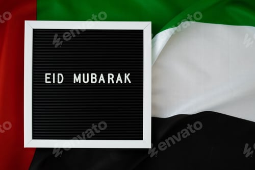 Preview: EID MUBARAK - happy holidays text frame on United Arab Emirates waving flag made from silk material
