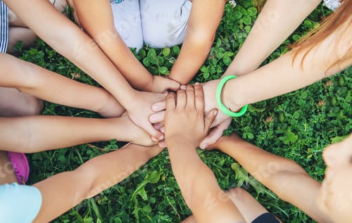 Preview: children's hands together on a background of grass. Selective focus.