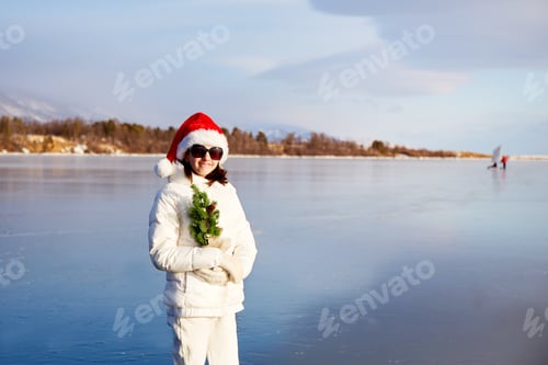 Preview: A girl in a Santa Claus hat and sunglasses holds a small Christmas tree