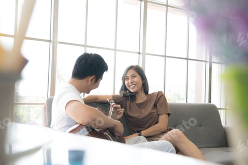 Preview: Woman Laughing While Man Plays Guitar Indoors