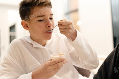 Visualização: Adolescente curtindo iogurte com uma colher em casa