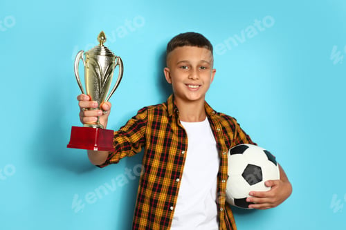 Preview: Happy boy with golden winning cup and soccer ball on blue background