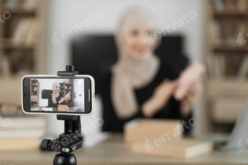 Preview: Focus on smart phone screen, pleasant arab woman filming video on modern phone camera