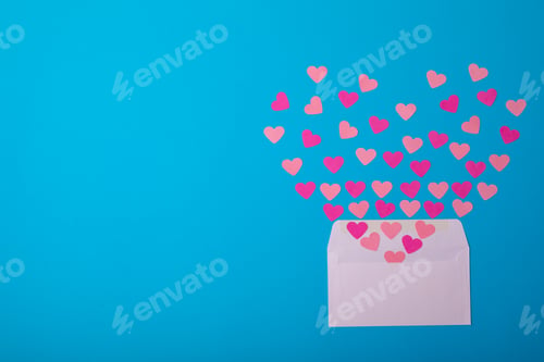 Preview: Overhead view of pink hearts coming out from white envelope on blue background, copy space