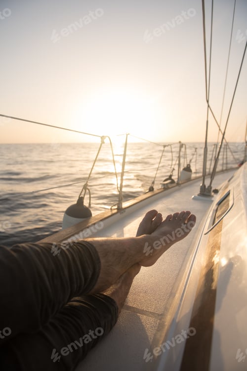 Preview: Man lying on edge of yacht on water