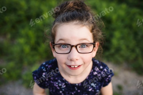 Preview: Portrait of cute girl wearing eye glasses looking up at camera