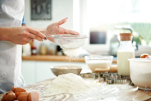 Preview: Woman sifting flour in kitchen
