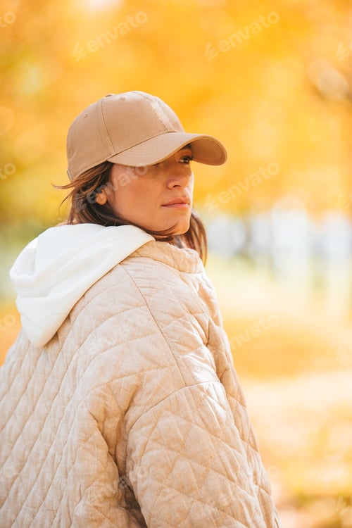 Preview: Fall concept - beautiful woman drinking coffee in autumn park under fall foliage