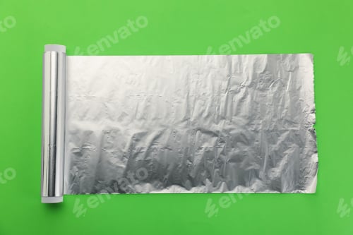 Preview: Roll of aluminum foil on green background, top view