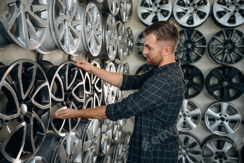 Preview: Choosing the right disk. Man worker is maintenance station with tires, wheels