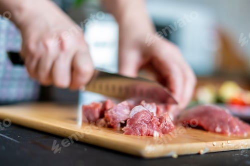 Preview: womans hands cut meat on a wooden board b