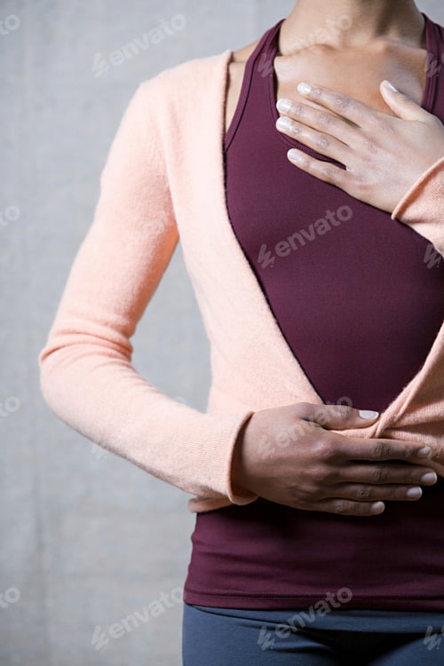 Preview: A woman standing confidently with her hand on her heart and another on her abdomen.