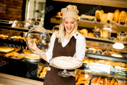 Preview: Bakery female worker posing with apple tart in baker shop