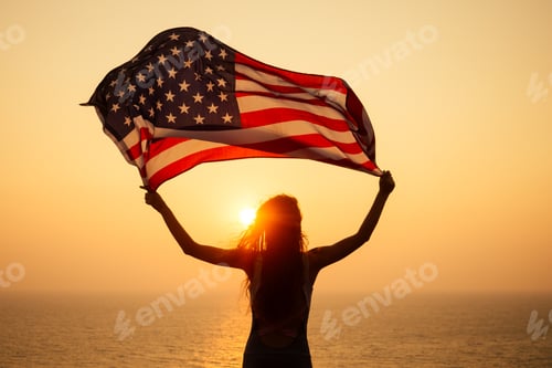Preview: woman holding USA flag and looking at sunrice