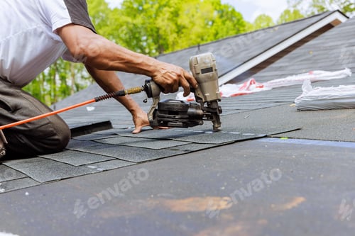 Preview: In addition to using an air pneumatic nail gun, a roofer installs new asphalt bitumen shingles