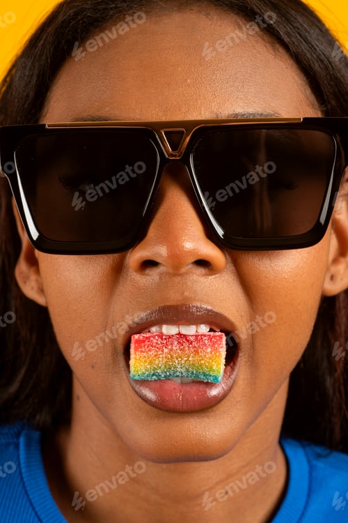 Preview: Fashion model eating colorful strip candy and wearing sunglasses