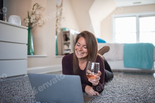 Preview: Smiling Woman Lying on Rug Using Laptop
