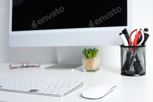 Vorschau: Moderne Schreibtischeinrichtung mit Computer, Tastatur, Maus, Brille, Pflanze und Zubehör