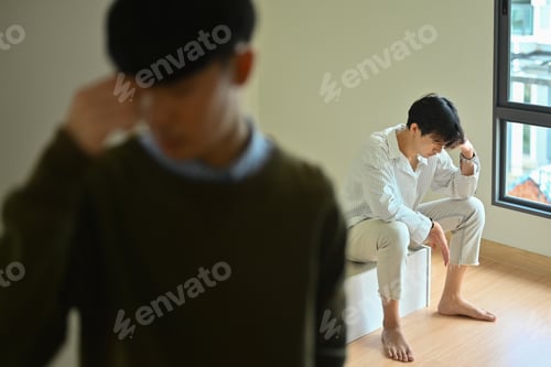 Preview: Quarreled gay male couple ignoring each other after quarreling at home.
