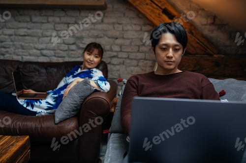 Preview: Asian male using laptop while his girlfriend chilling near him