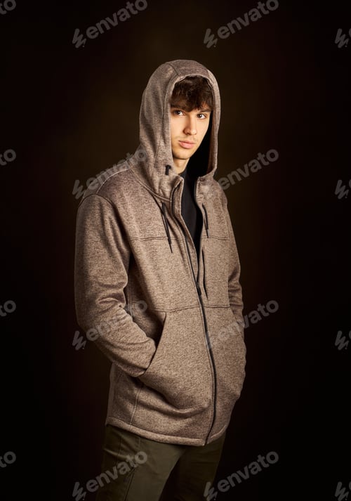 Preview: Young man wearing hoodie posing in studio with dark background