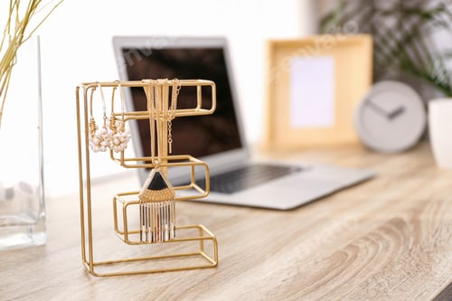 Preview: Stylish workplace interior with jewelry holder on wooden table near window. Space for text