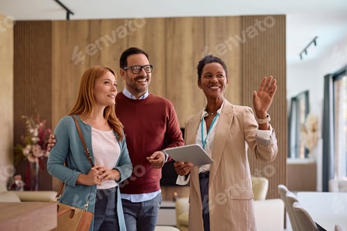 Preview: Happy black real estate agent using digital tablet while showing new house to a couple.
