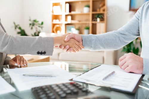 Preview: Handshake of businessman and businesswoman sitting by table