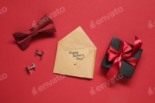 Preview: Card with phrase Happy Father's Day, gift box and men accessories on red background, flat lay