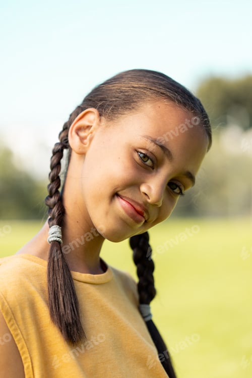 Preview: Portrait of biracial schoolgirl smiling in sports field at elementary school