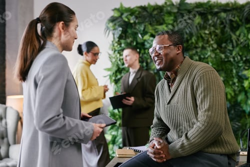 Preview: Woman With Tablet Discussing Work With Black Man In Business Setting