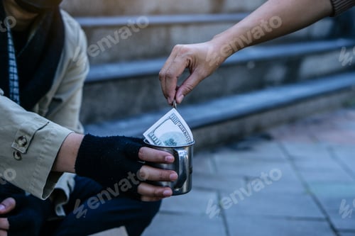 Preview: Woman giving money to homeless beggar man sitting in city.Giving concept.