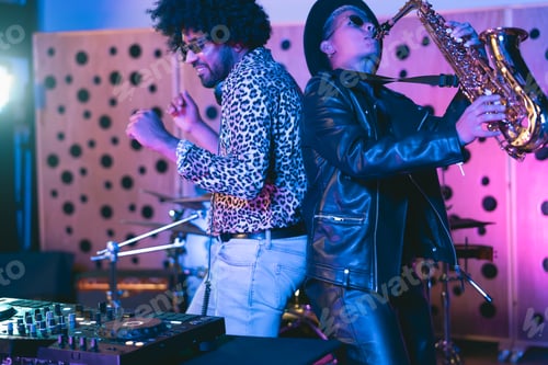 Preview: Young happy people playing music with dj mixer and saxophone in house studio