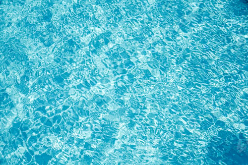 Preview: Transparent water in the pool with glare and waves, water abstract background. Vacation concept