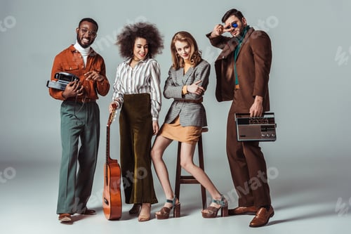 Preview: multiethnic retro styled friends with guitar and vintage radio on grey