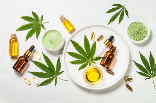 Preview: Cannabis oil and green leaves at white table