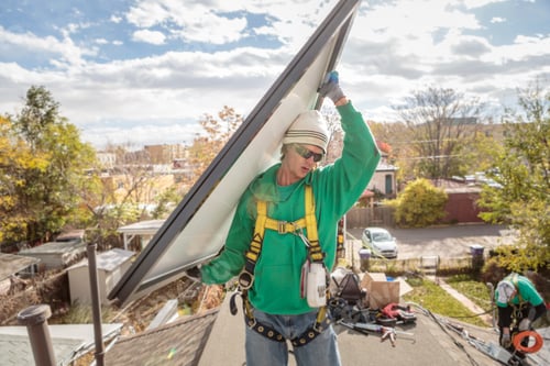 Preview: Construction crew carrying a solar panel on roof of house