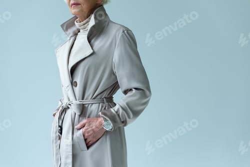 Preview: cropped view of senior lady in trench coat, isolated on grey