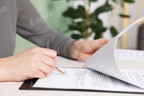 Preview: Woman putting signature on document at white table, closeup