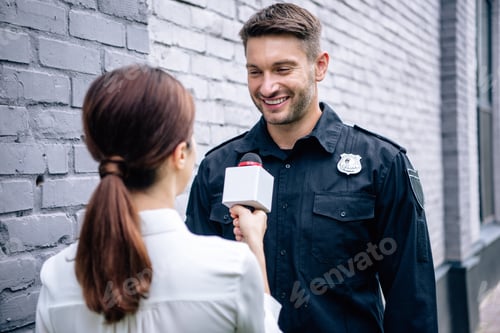 Preview: journalist holding microphone and talking with handsome policeman in uniform