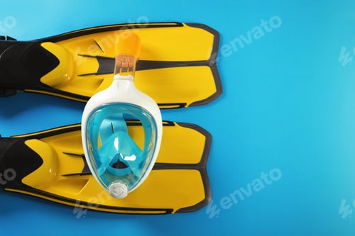 Preview: Pair of yellow flippers and diving mask on color background, top view with space for text