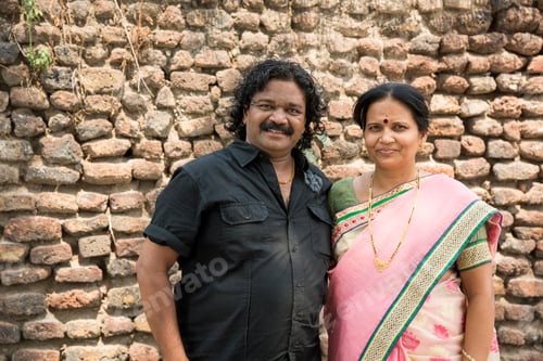 Preview: Smiling young couple in front of brick wall