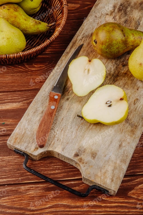 Preview: side view of fresh ripe pears and halves on a wooden cutting board with kitchen knife