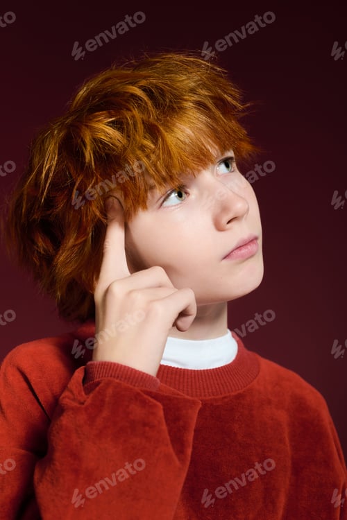 Preview: Redhead boy in casual fashion poses thoughtfully in a vibrant studio setting