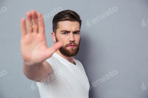 Preview: Portrait Of A Casual Man Showing Stop Sign Over Gray Background