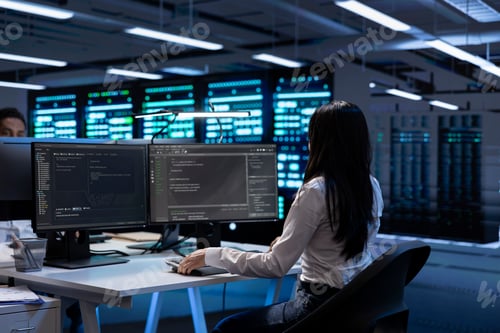 Preview: Programmer in data center checking equipment performance on computer