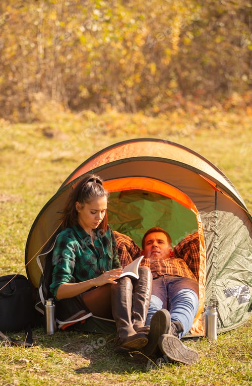 Preview: Young girl reading a book with her friend next to the tent